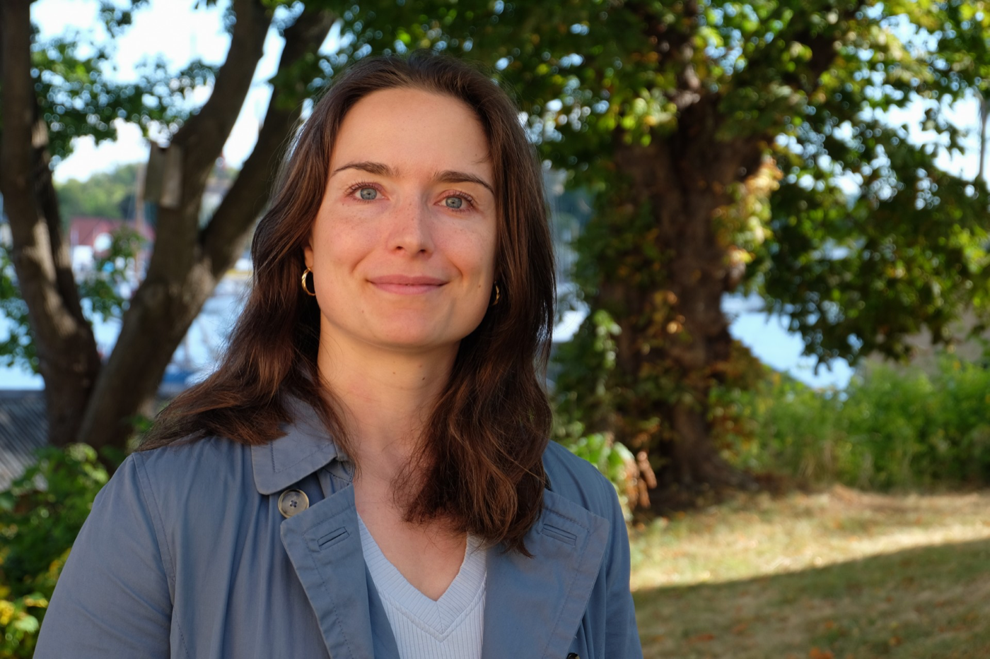 Laura Löfgren utomhus framför grönskande träd